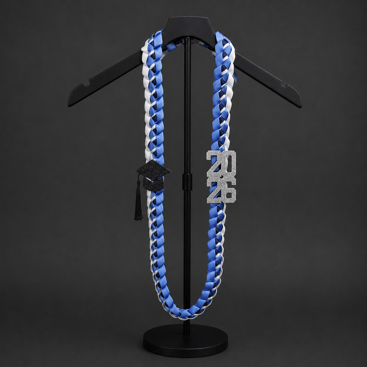 3 strand Blue and white custom Ribbon Lei on a black stand against a dark background